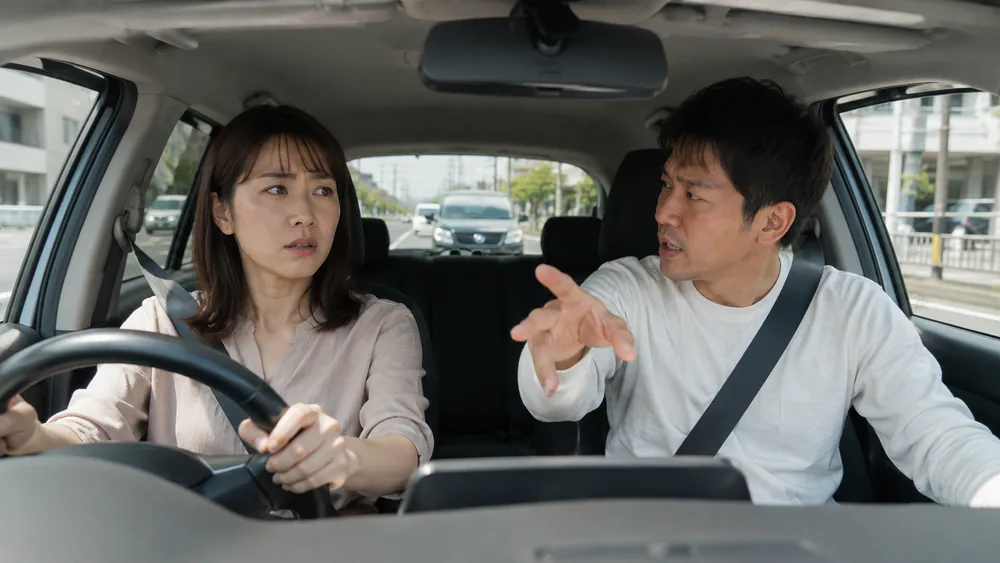 助手席の家族に見守られて練習する運転者のイメージ